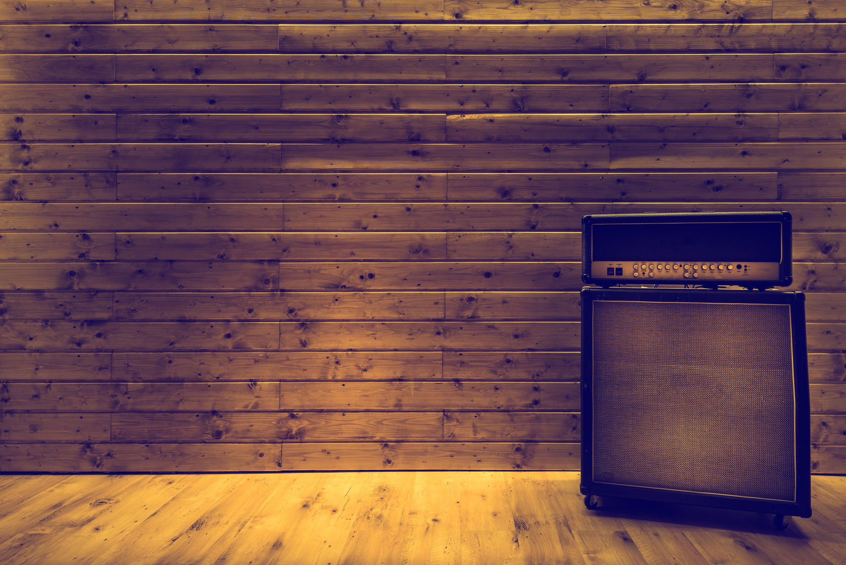 Guitar amplifier on wooden wall and floor, music studio